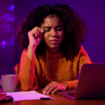 Frustrated woman in front of laptop, struggling with low podcast visibility.
